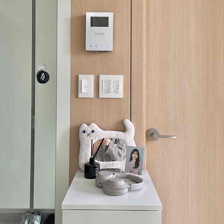 白と木目調が調和する玄関、猫型のミウミラーとディフューザー、ヘッドホンが配置された整った空間