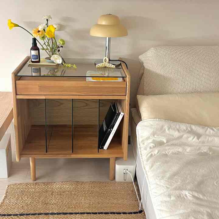 黄色のアクセントがあるナチュラルな寝室、ベッドリネンとナイトテーブル上の照明と花の装飾が配された雰囲気あるインテリア