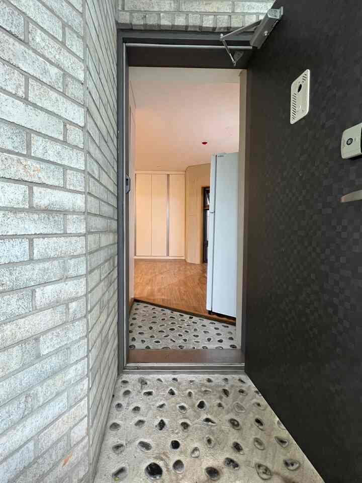 ブラウンの木製床と白いシューズラックが配置された自然な石畳の玄関の雰囲気あるインテリア