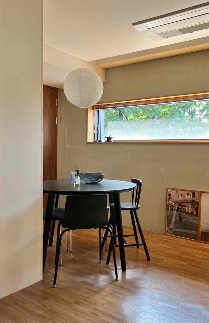 ウッドトーンの床と黒いダイニングテーブル、椅子が配置されたシンプルで開放感のある二人暮らし用ダイニングルーム