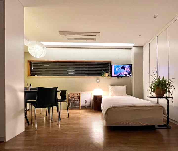 ホワイトとブラウンのトーンのモダンで落ち着いた寝室、シングルベッドとダイニングセットが配置された空間