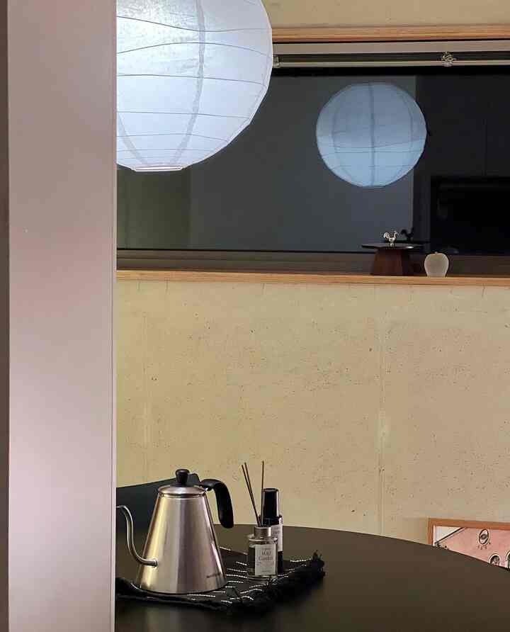 グレーのコンクリート壁と黒いテーブル、間接照明が配置されたインダストリアルスタイルのワンルーム空間