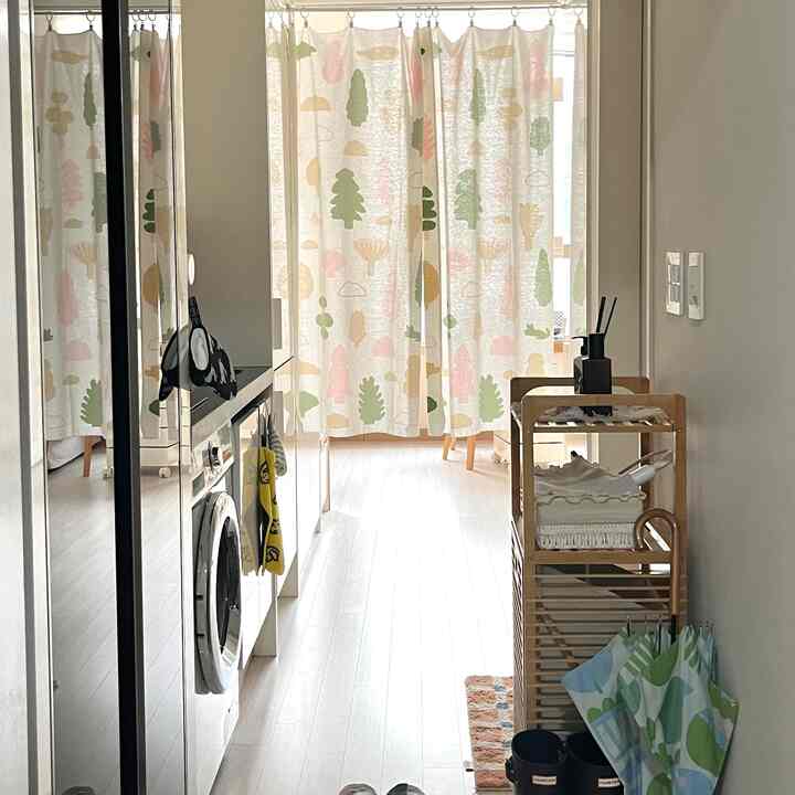 白と木目調のキッチン空間、ビルトイン洗濯機と収納アイテムが配置された実用的な狭い部屋