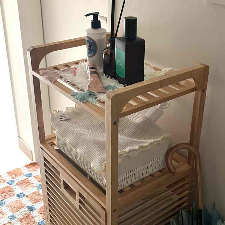 ナチュラルな木目調のバスケット棚が置かれたキッチンの一角、ベージュの布とバター色のキッチンクロスが落ち着いた雰囲気のインテリア