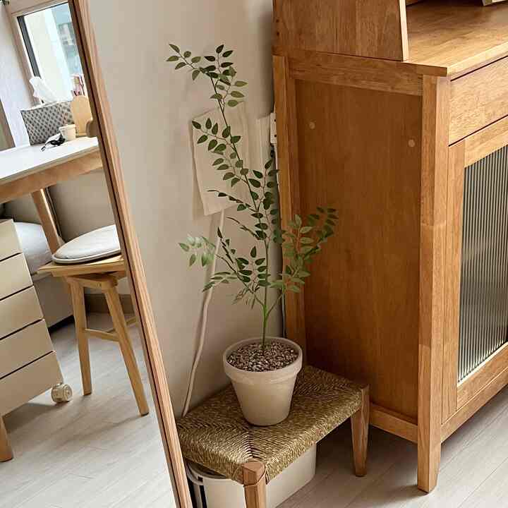 ナチュラルな色調のダイニングスペース、木製家具とスツールの上の造花が配置された温かみのあるインテリア