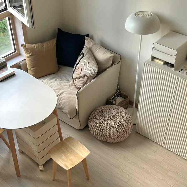 ホワイトと木目調が調和したリビングの休憩スペース、一人用ソファと楕円形テーブルが配置されたナチュラルモダンなインテリア