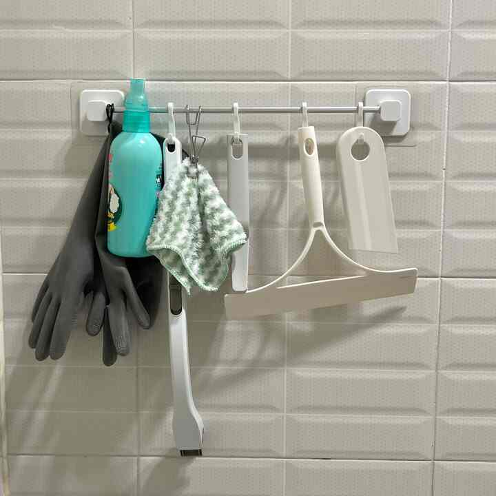 白を基調としたバスルームの壁に整理された清掃用品が配置された、一人暮らし向けのすっきりとした空間