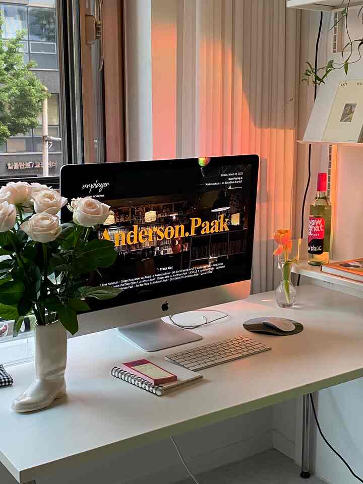 白とアイボリーのトーンのホームオフィス、シンプルなデスクに大きなアイボリーブーツ型の花瓶とコンピューターが配置された雰囲気のあるインテリア