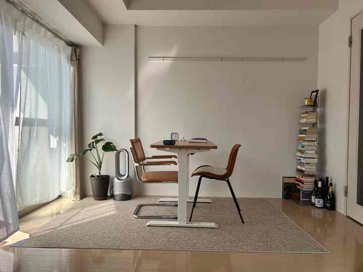 ホワイトとベージュのトーンのシンプルなダイニングルーム、木製チェアと植物が配置された落ち着いたホームオフィス空間