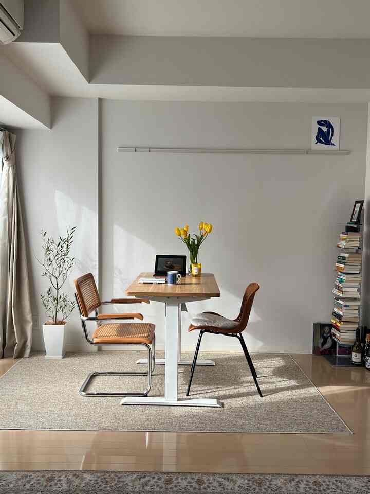 木目調とベージュトーンのナチュラルなホームオフィス、ラタンチェアとデスクが配された落ち着いた空間