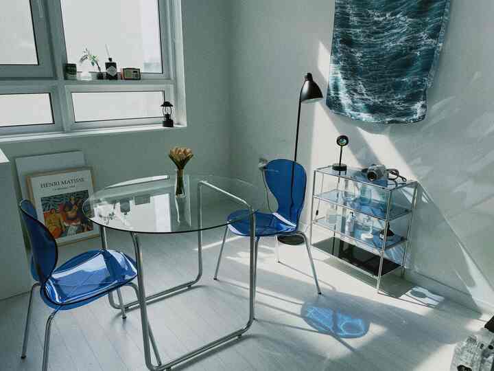 青と透明素材の家具が置かれたミニマルなダイニング、清潔で明るい雰囲気のインテリア