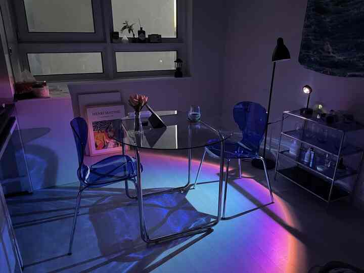 透明なガラステーブルと青い透明な椅子が配置されたミニマルでモダンな照明のあるダイニングルーム