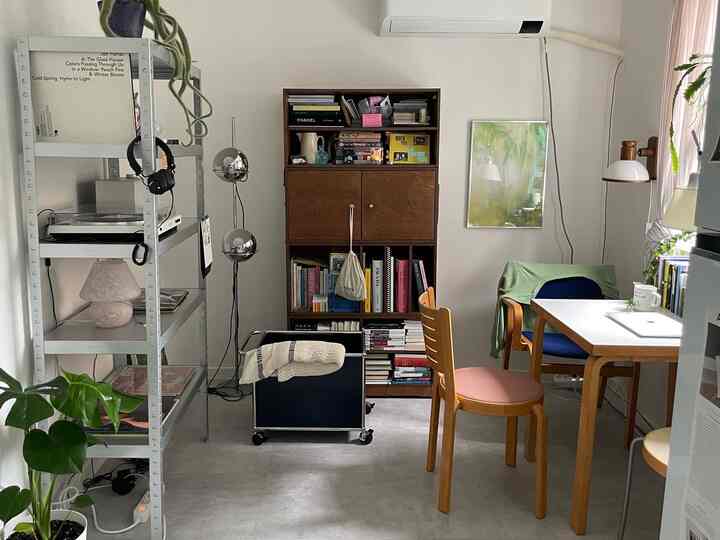 ホワイトと木目調のリビング、書棚とサイドテーブルが配置され、自然光と植物が調和した雰囲気のあるインテリア