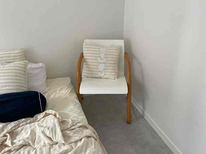 白とベージュの落ち着いた色調の寝室、トーネットのヴィンテージチェアとストライプのクッションが配置された雰囲気のある空間