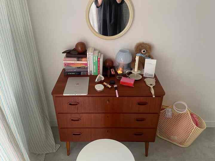 ベージュ色調のウォークインクローゼット、ヴィンテージ木製チェストにオブジェと本が配置された雰囲気のあるインテリア