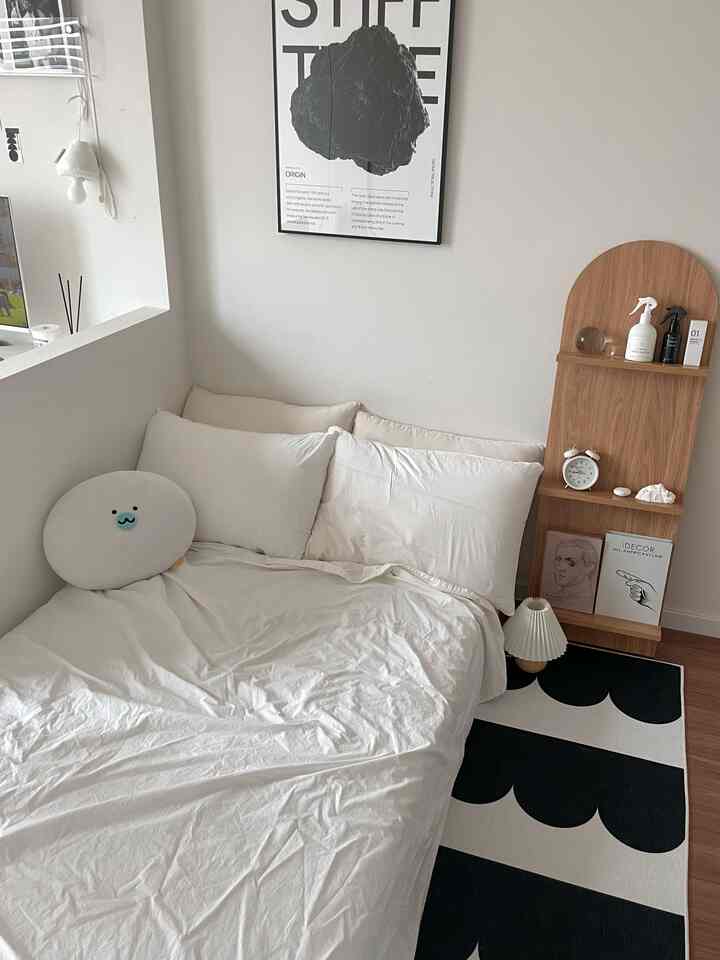 ホワイトとブラックの調和が美しいミニマルモダンな寝室、木目調の棚とテーブルランプが配置された雰囲気のある趣味空間