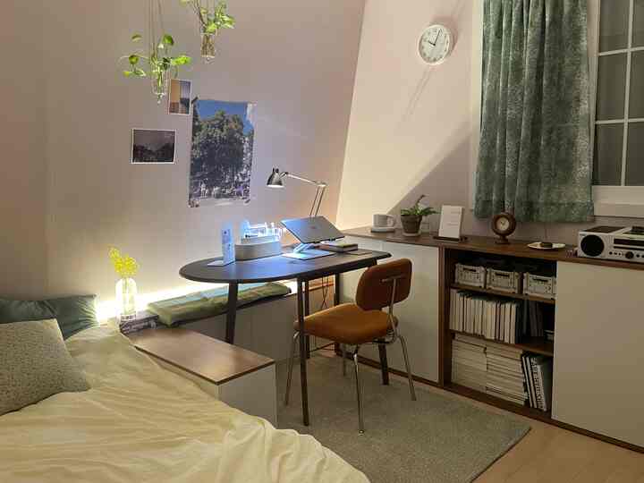 白い壁と緑のカーテンが調和した寝室のホームオフィス、机とベッドが居心地の良い雰囲気を醸し出すインテリア