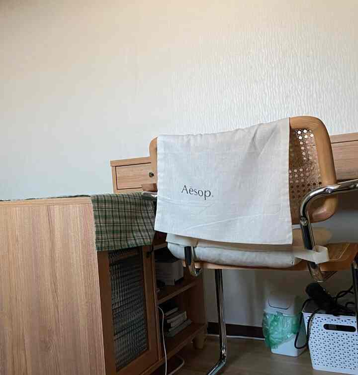 柔らかな木目調の小さな部屋、ウッド家具とラタンのアームチェアが配置されたナチュラルな雰囲気のインテリア