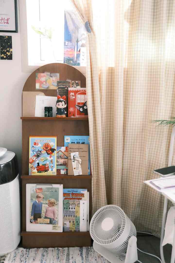 暖かいナチュラルカラーの玄関スペース、木製マガジンラックと本、ベージュのチェックカーテンが落ち着いた雰囲気を演出