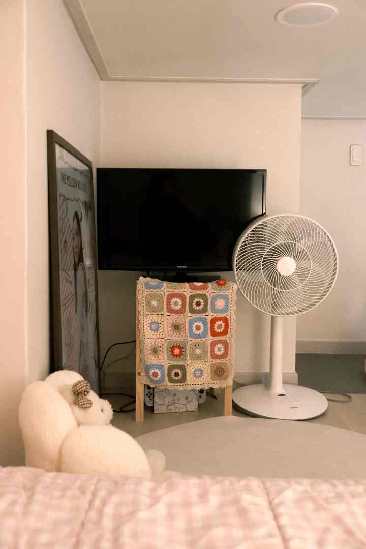 白とベージュの色調の寝室、ベッドとテレビ台が配置された落ち着いた雰囲気のインテリア