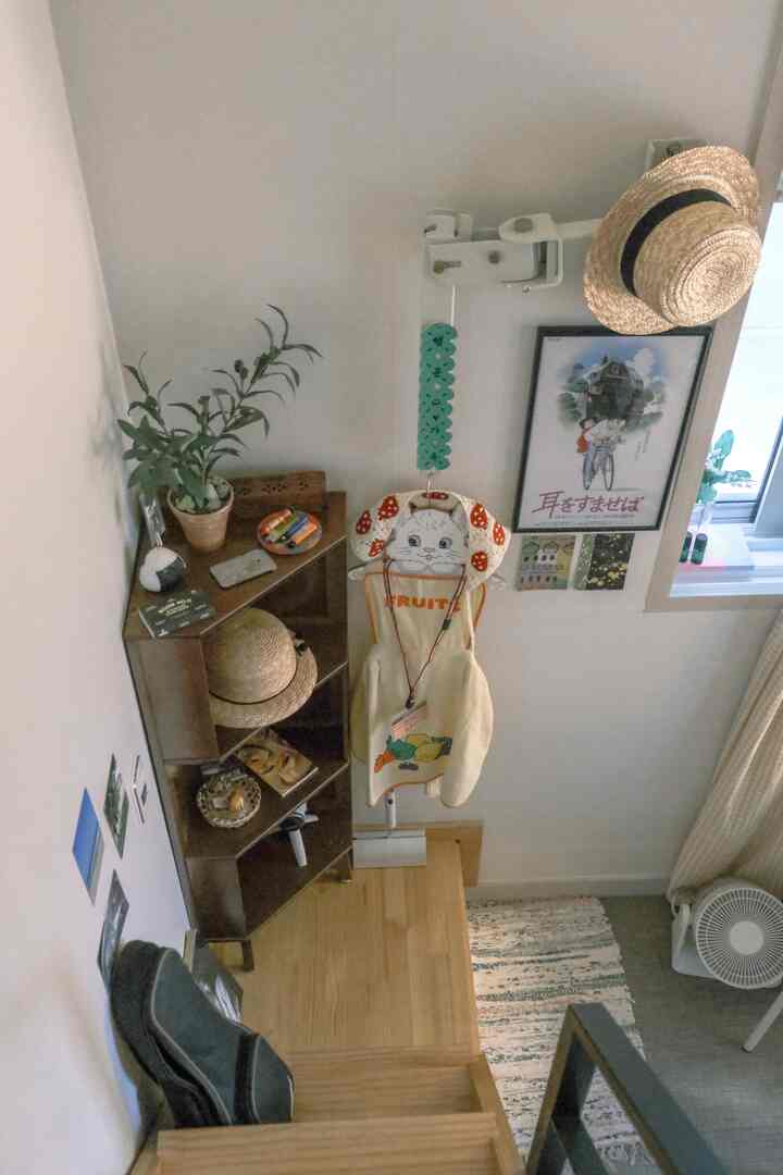 ナチュラルな木目調の狭い階段入口、コンパクトな収納棚と植物が配置された雰囲気のあるインテリア