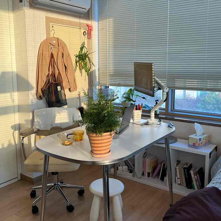 シルバー脚のラウンドホワイトデスクとオフィスチェアが配置されたモダンなホームオフィス空間