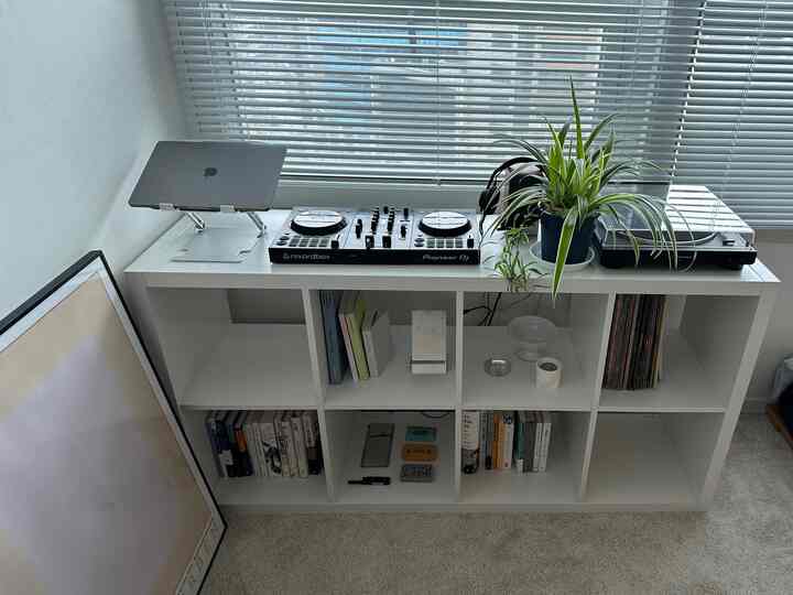 白を基調とした多目的本棚が配置され、DJ機器とブラインドが調和した清潔感のある書斎空間