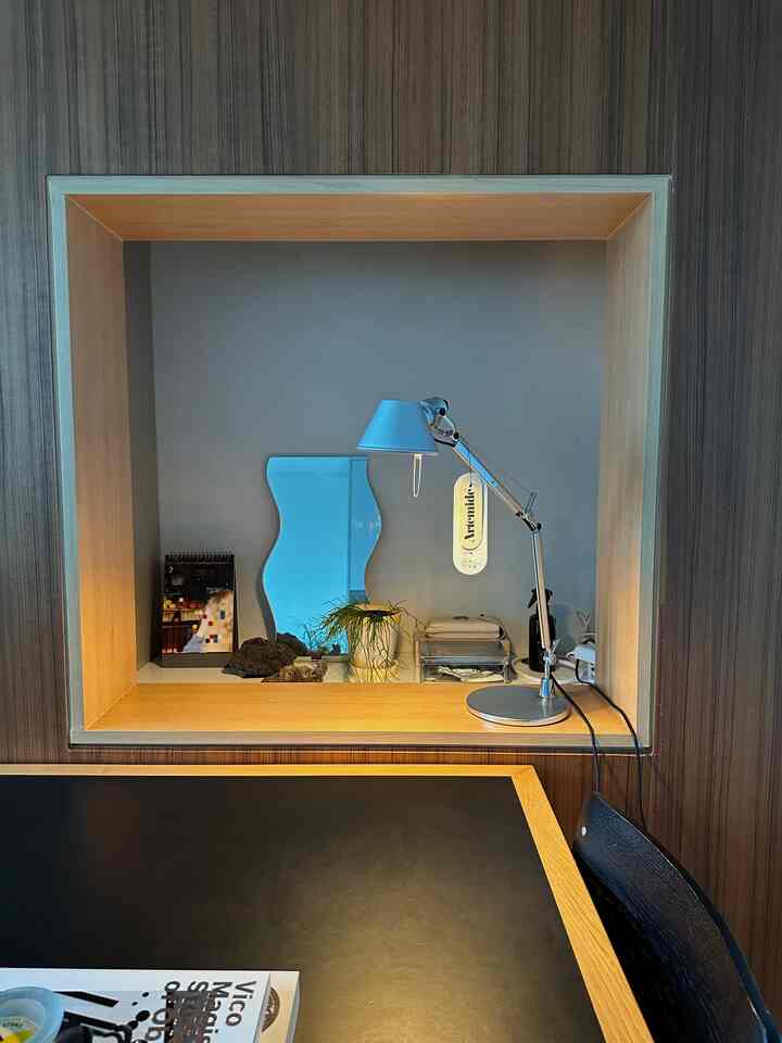 ダークブラウンの壁とナチュラルウッド調のニッチがあるキッチン、照明とオブジェが配置された雰囲気のあるテーブルスペース