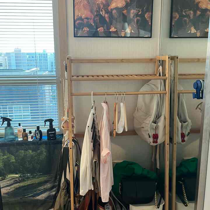 ベージュの壁と木製のコートハンガーが配置された、ブラインド付きの窓がある印象的なクローゼットスペース