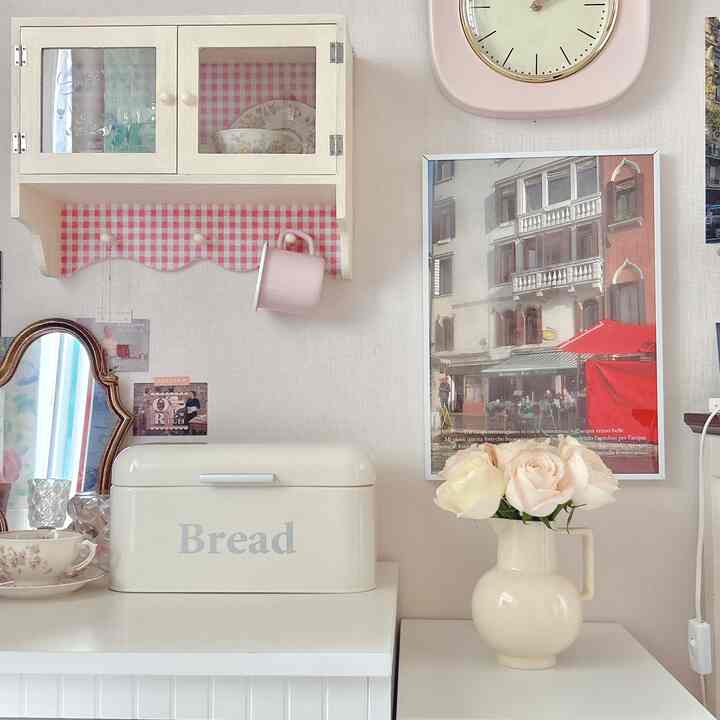 ホワイトとピンクの色調のキッチンコーナー、ヴィンテージアイテムとポスターが配置された雰囲気のある空間