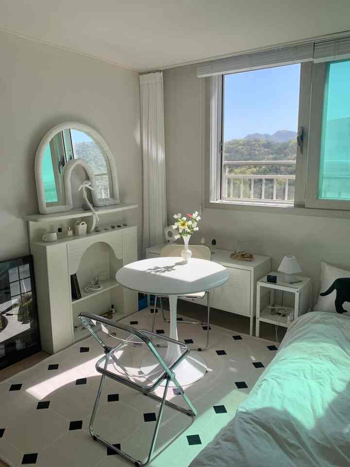 明るいホワイト調の寝室とおうちカフェ空間、丸テーブルと透明な椅子が配置された雰囲気のあるインテリア