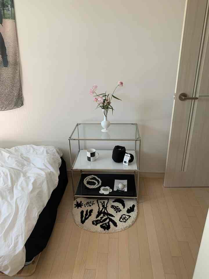 白と黒のトーンの寝室、ガラス棚に花瓶と小物が配置されたシンプルなインテリア