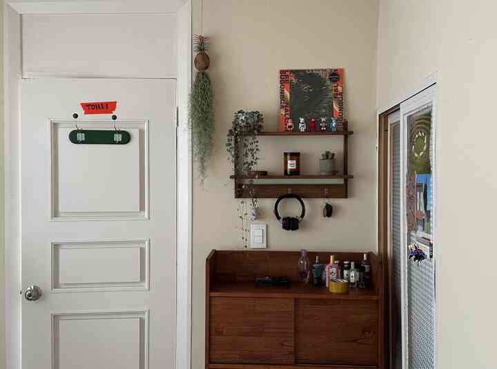 明るい白い壁とドア、ブラウンの木製キャビネットと棚が配置されたナチュラルな雰囲気のインテリア