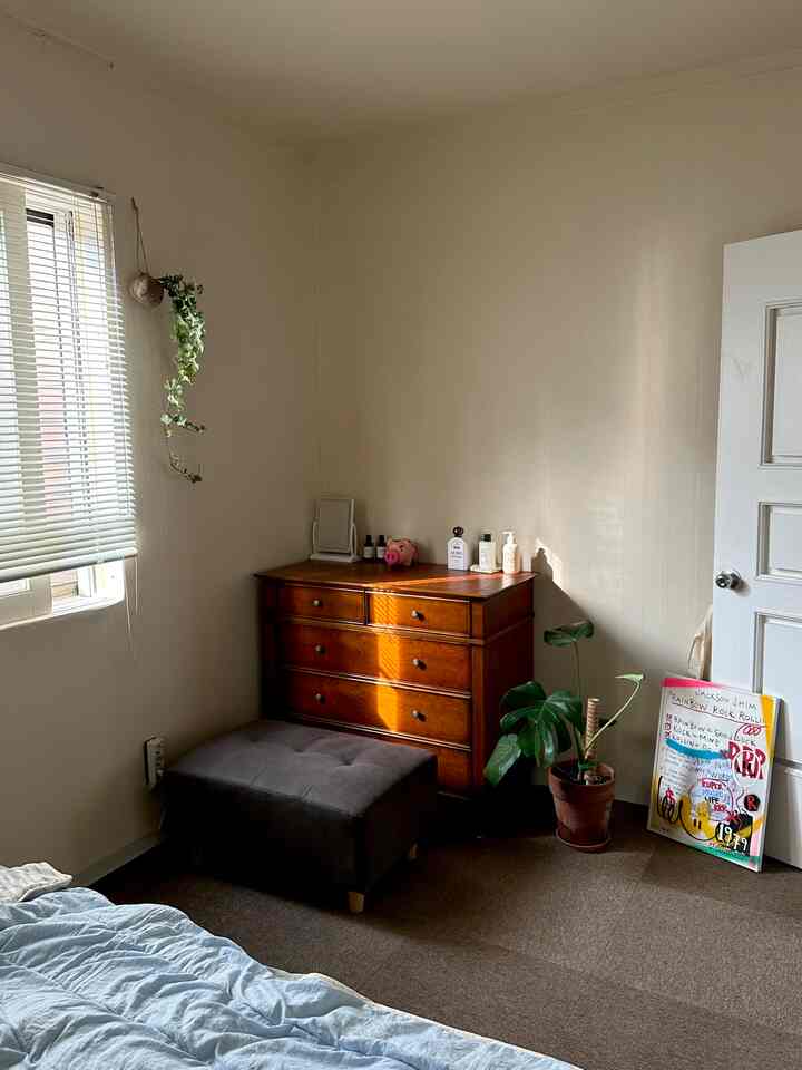 白い壁と茶色の化粧台が配置されたシンプルなウォークインクローゼット、ブラインドから自然光が差し込む雰囲気のあるインテリア