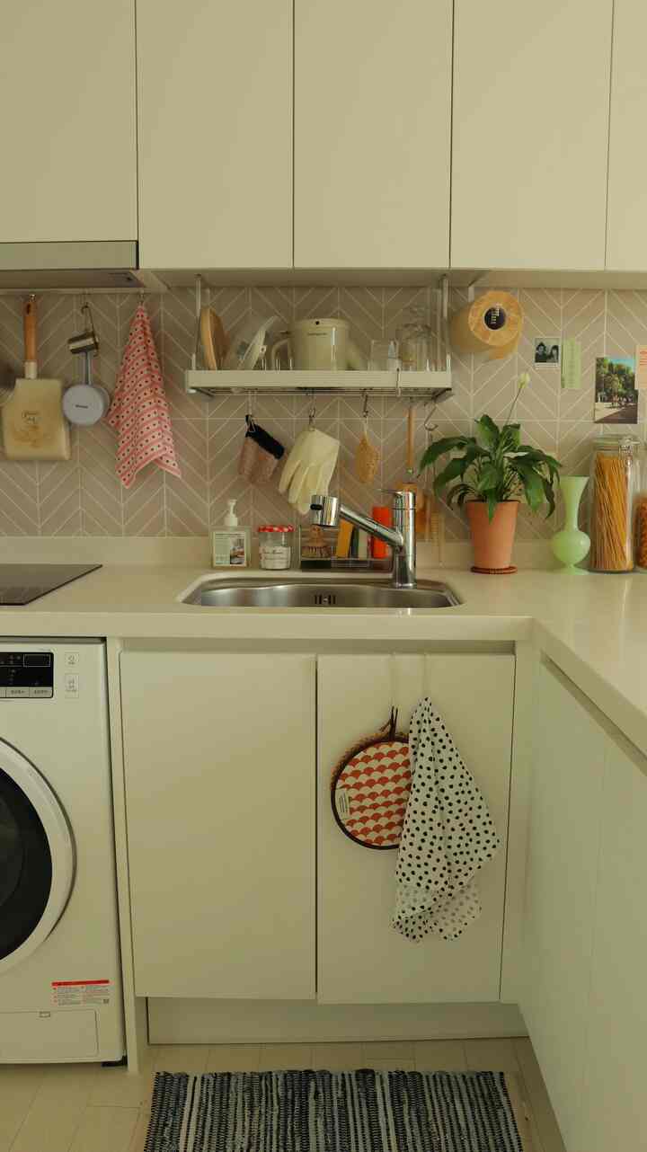 白と木目調が調和したキッチン、シンクと整った収納アイデアが印象的なナチュラルな空間