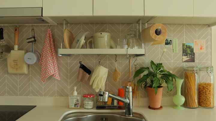 ナチュラルな色調のキッチン、シンクと多用途収納棚、タオル、鉢植えの植物が調和した清潔感のあるインテリア