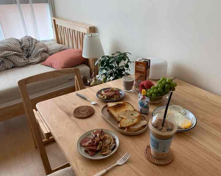 ナチュラルカラーとホワイトの調和がある6畳の寝室、折りたたみ式ダイニングテーブルと小さなベッドが配置された温かみのあるワンルームインテリア