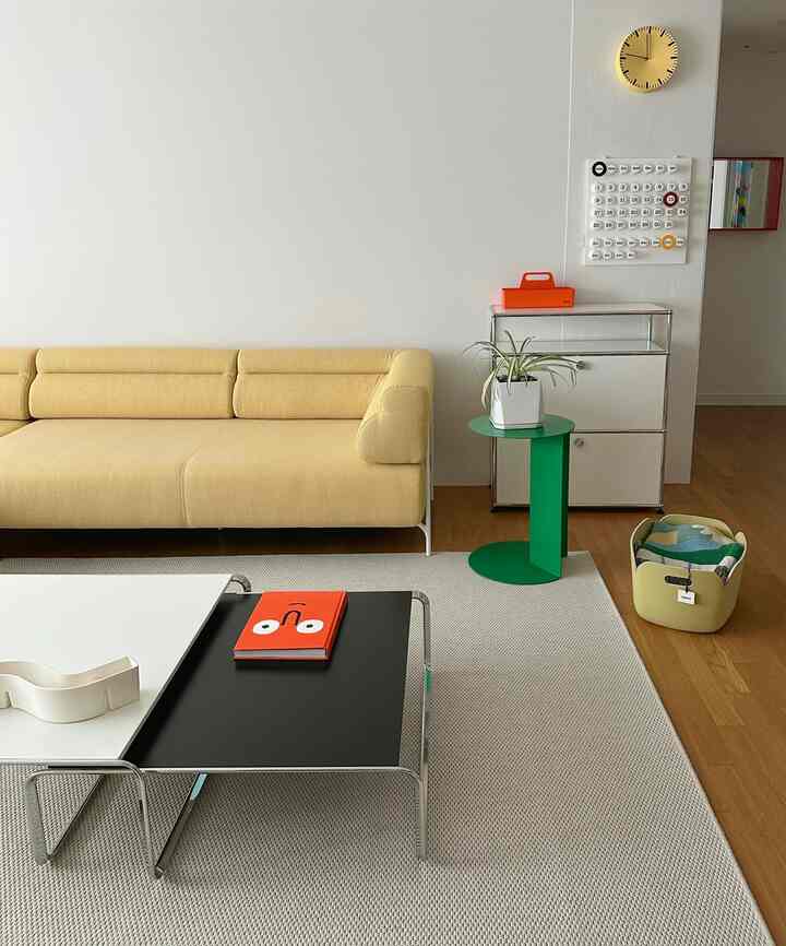 ナチュラルカラーのリビング、黄色いソファと黒白のコーヒーテーブル、緑のサイドテーブルが配置されたミニマルでモダンな印象的な空間