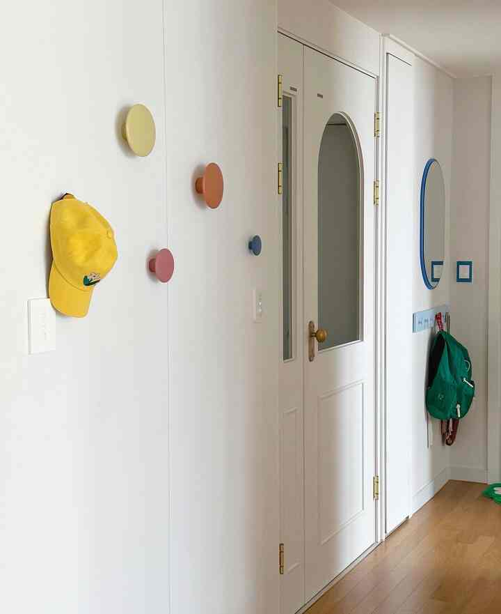 白と木目調の玄関、カラフルなMuutoのThe Dotsコートラックと二つの鏡が配置された清潔で実用的なインテリア