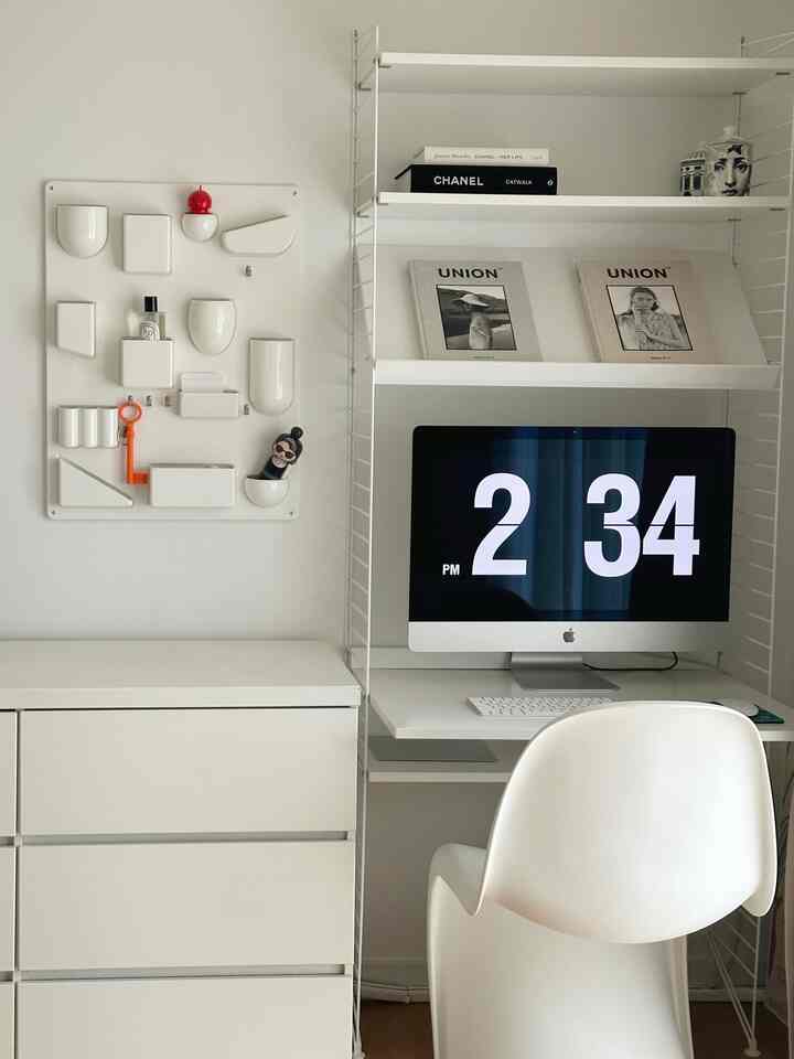 白を基調とした寝室のホームオフィス、机とチェストがすっきりと配置されたミニマルな空間