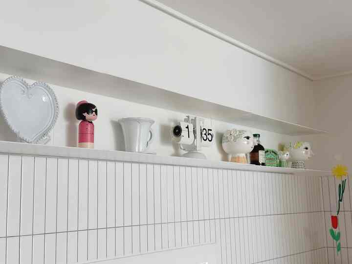 明るいホワイトトーンのキッチン空間に、ハート型の皿、人形、時計などのデコ小物が配置された印象的なインテリア