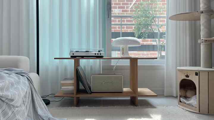 白とウッドトーンが調和したリビング、キャットタワーとテーブルランプが配置されたモダンな空間