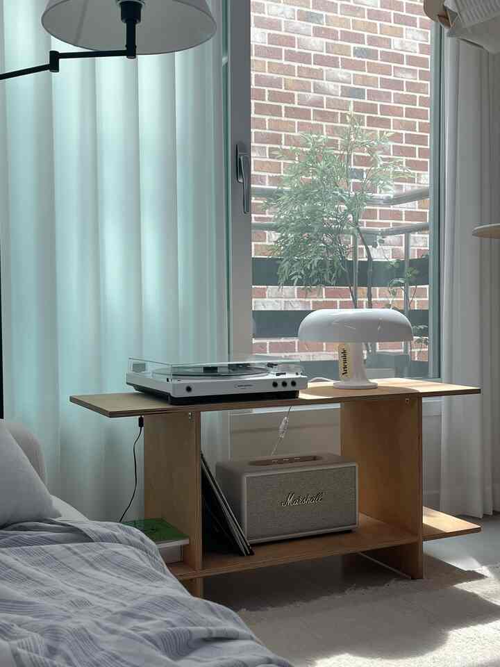 白と木目調のリビング、オーディオテクニカのターンテーブルとマーシャルスピーカー、優雅なテーブルランプが配置された雰囲気のあるインテリア