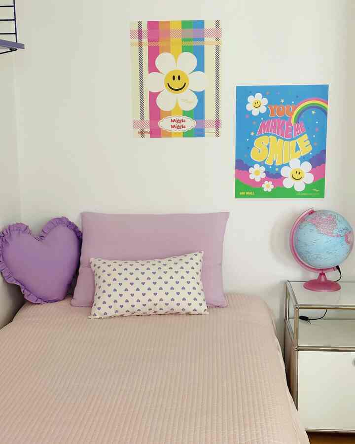 パステル調とライトブラウンの寝具がある子供部屋、ハート型のクッションとカラフルな壁デコが印象的な居心地の良い空間