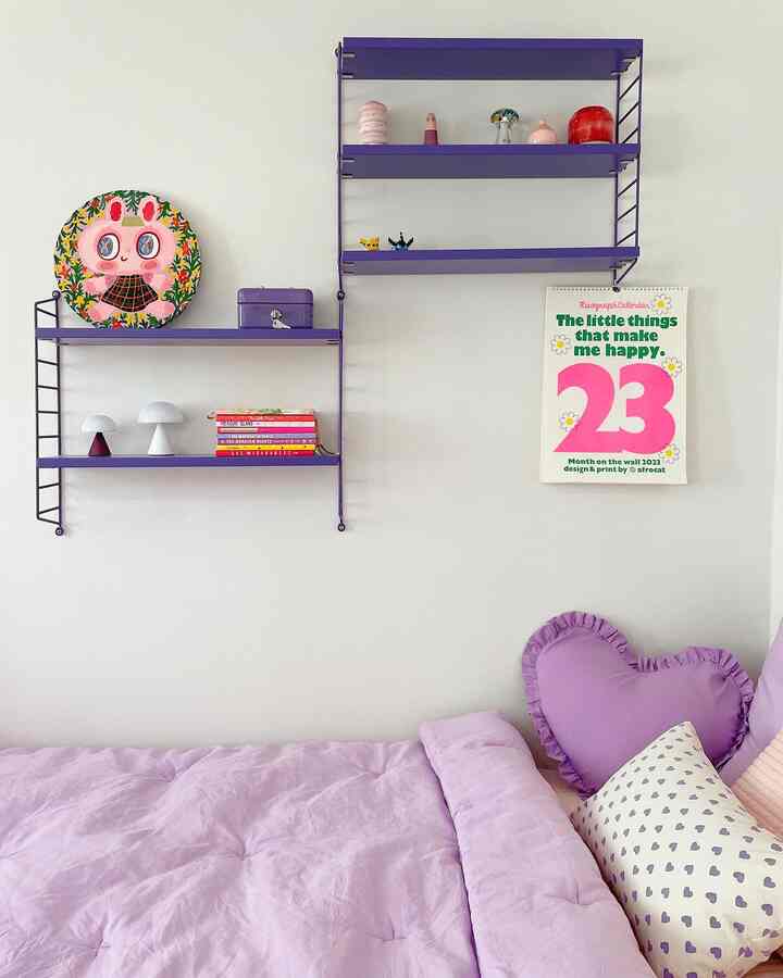 パープルのトーンの子供部屋、紫色の壁棚とベッドにかわいい小物が飾られた雰囲気のあるインテリア