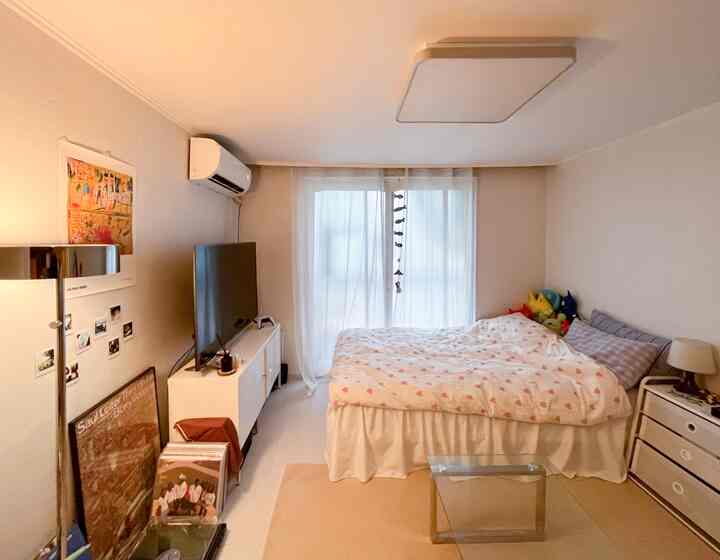 白とベージュの色調の寝室、ダブルベッドとホワイトのドレッサーが置かれた落ち着いた空間