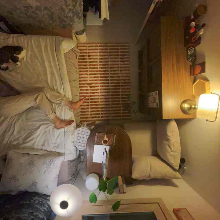 ベージュとブラウンの落ち着いた寝室、ベッドとソファ、デスクが配置された居心地の良い小さな部屋のインテリア