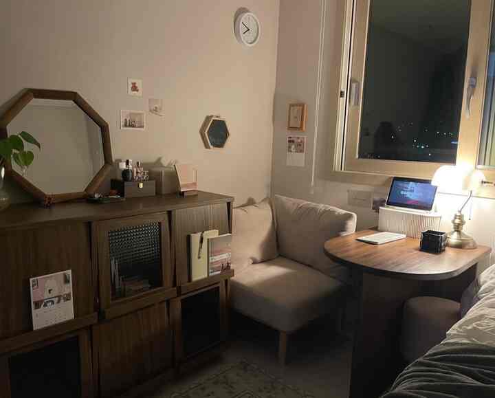 ベージュと木目調の色調の小さなリビング、コーナーソファと木製テーブルが配置された雰囲気のあるインテリア