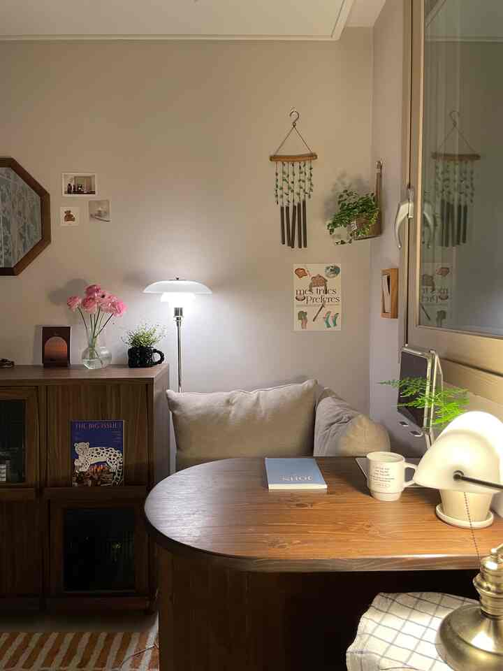 暖かい木目調とベージュの壁が印象的な落ち着いた1人用リビングコーナー、ソファとデスク、柔らかな照明が配置された空間