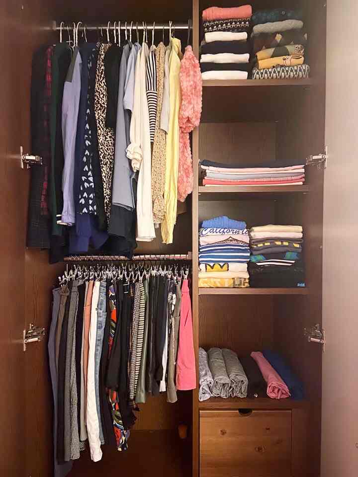 ダークブラウン色調のクローゼット内に整然と収納された多彩な衣類がある落ち着いた空間